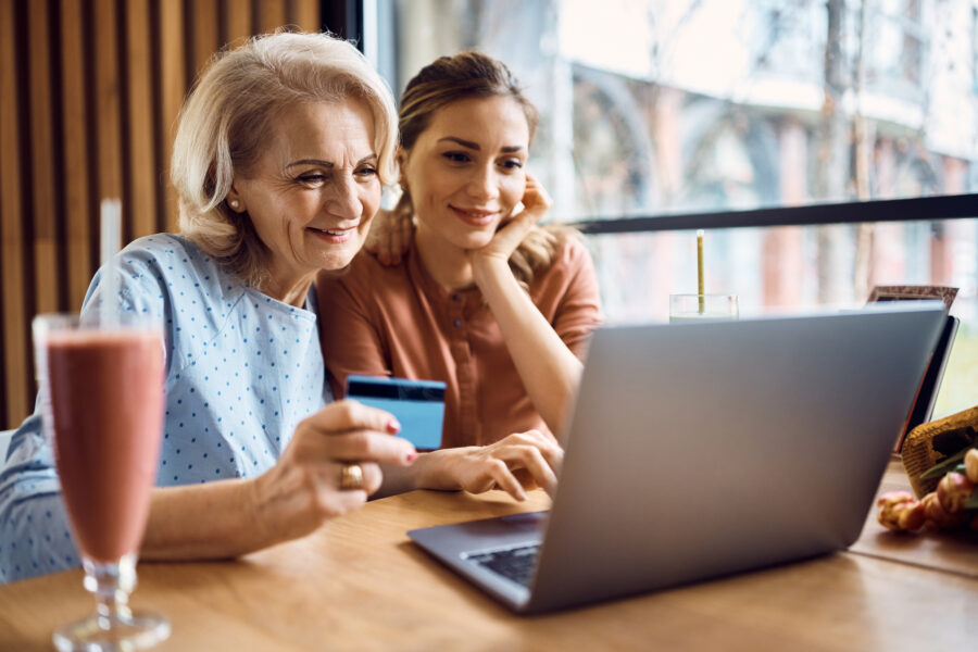Happy Senior Woman Enjoying In Online Booking With Her Daughter In A Cafe.